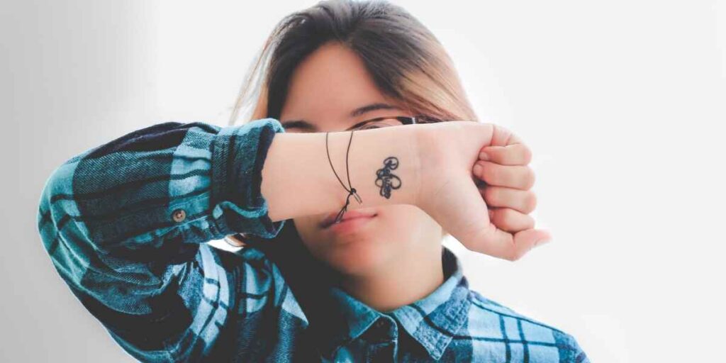 A woman showcasing her wrist tattoo, highlighting the beauty and artistry of wrist tattoos in a close-up view.
