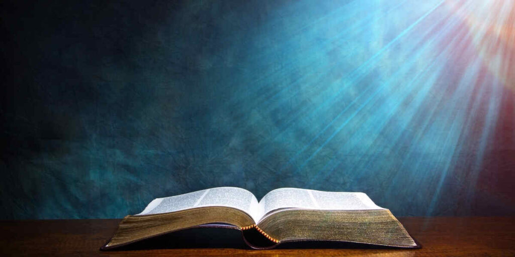 An open Bible on a wooden table, illuminated by sunlight, symbolizing the Biblical Meaning of 1234: Creation to Completion.
